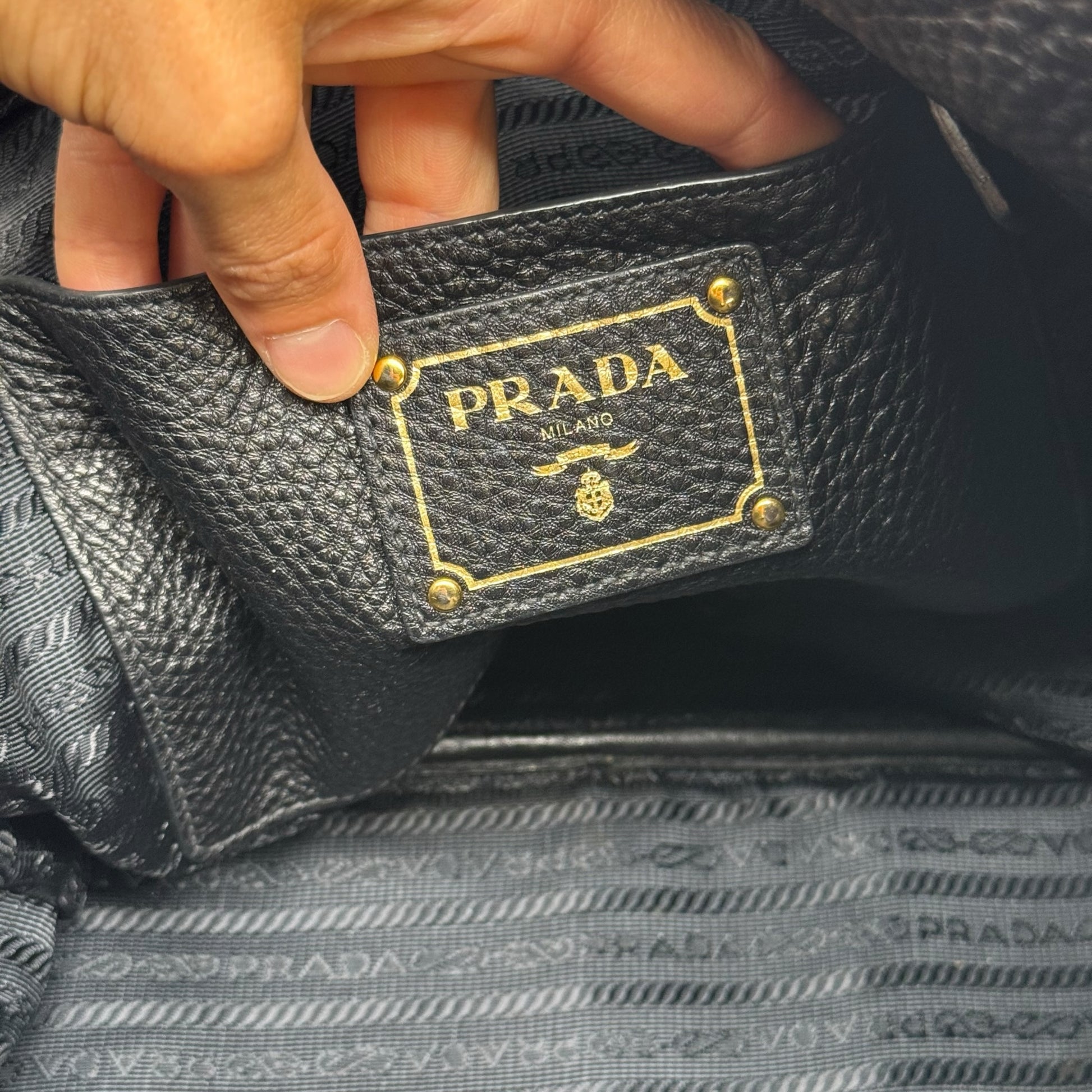 Dettaglio interno della borsa tote Borse Vintage Prada in pelle nera martellata con placca logo dorata