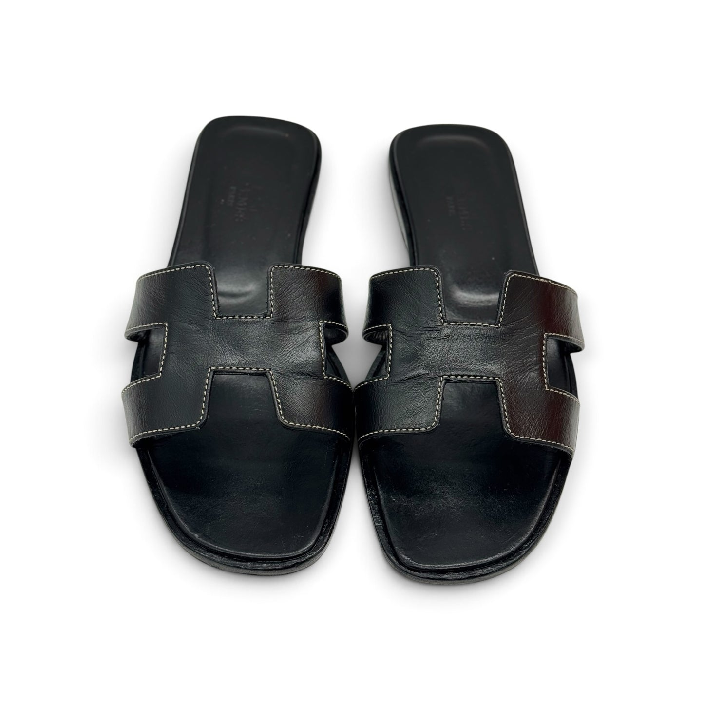Sandali flat Borse Vintage in pelle nera con iconico design a H e cuciture a contrasto su sfondo bianco