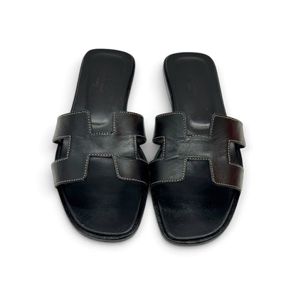 Sandali flat Borse Vintage in pelle nera con iconico design a H e cuciture a contrasto su sfondo bianco