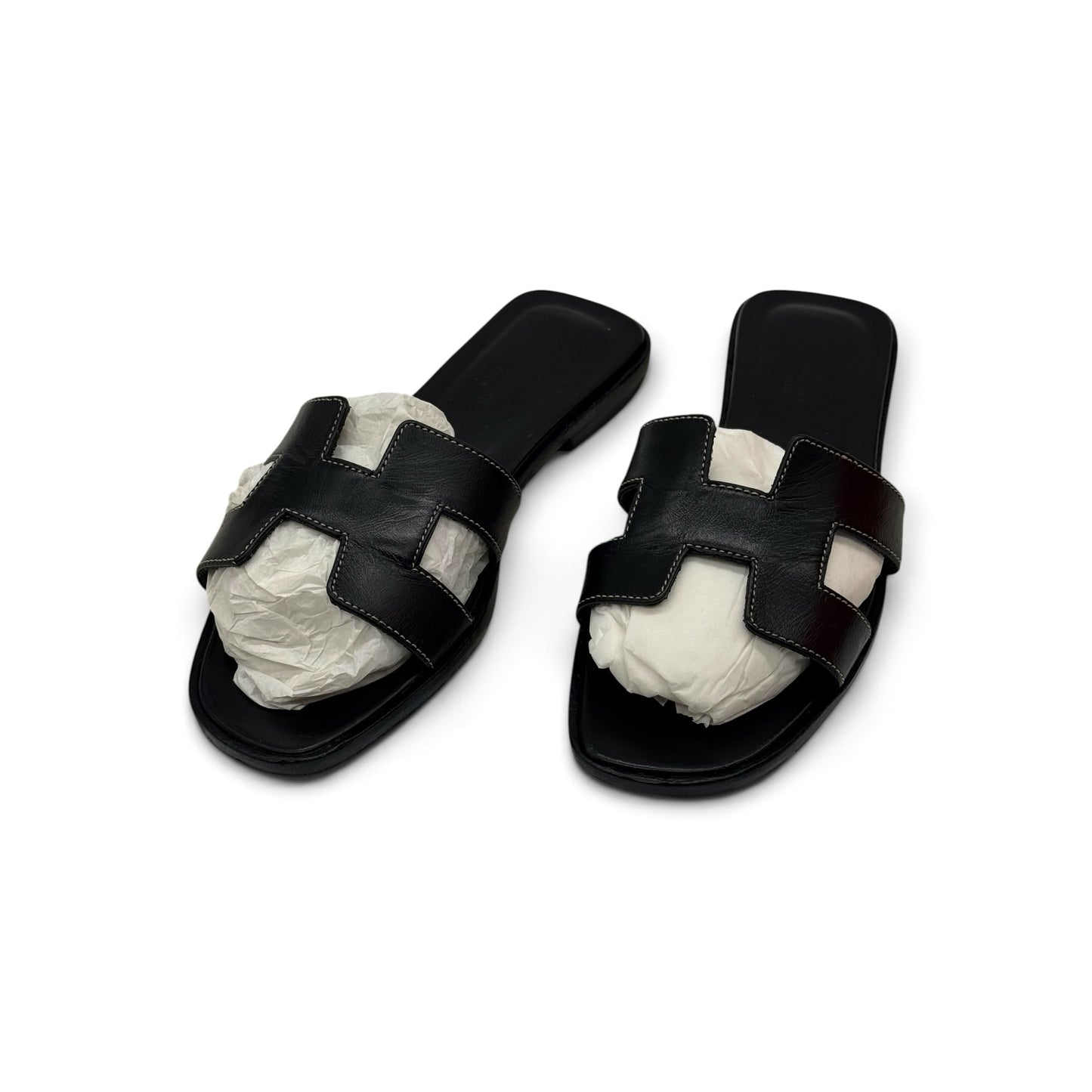 Sandali flat Borse Vintage in pelle nera con iconico design a H e cuciture a contrasto su fondo bianco